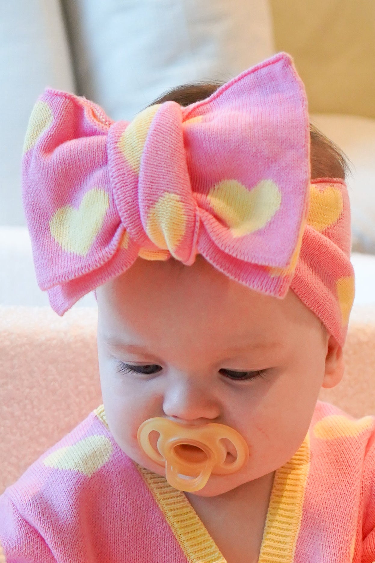 Baby girl wearing Buttercup Princess loveheart knit headband in pink and butter yellow cotton knit close up