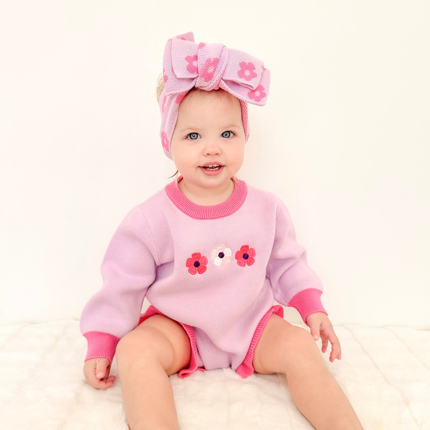 Baby girl wearing the La Dolce Lollie Blossom knit outfit with matching knitted headbow in soft purple and pink cotton knit