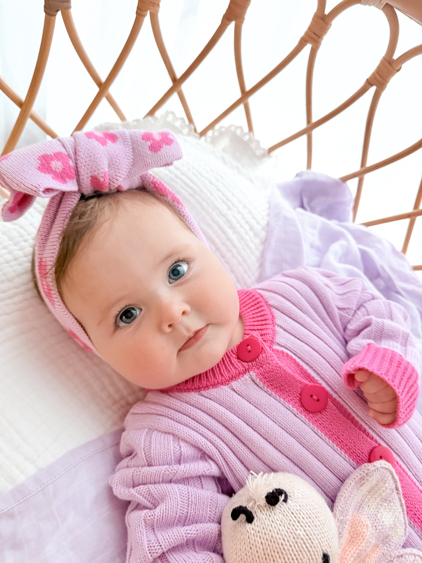Baby wearing the La Dolce Lollie knitted head bow and matching pink and purple cotton knit romper