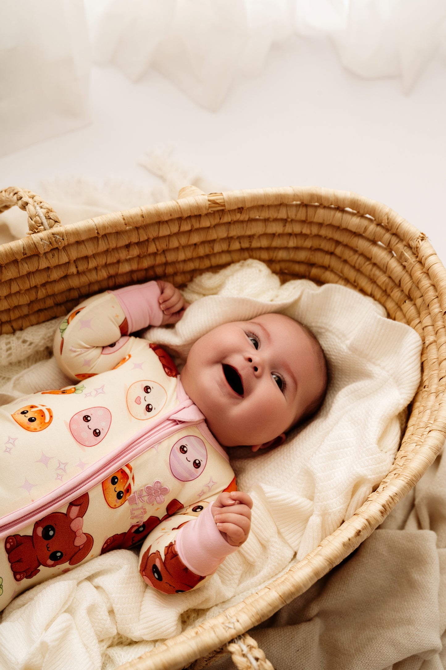 Baby lying in woven bassinet wearing Pink Easter Bunny bamboo zip romper
