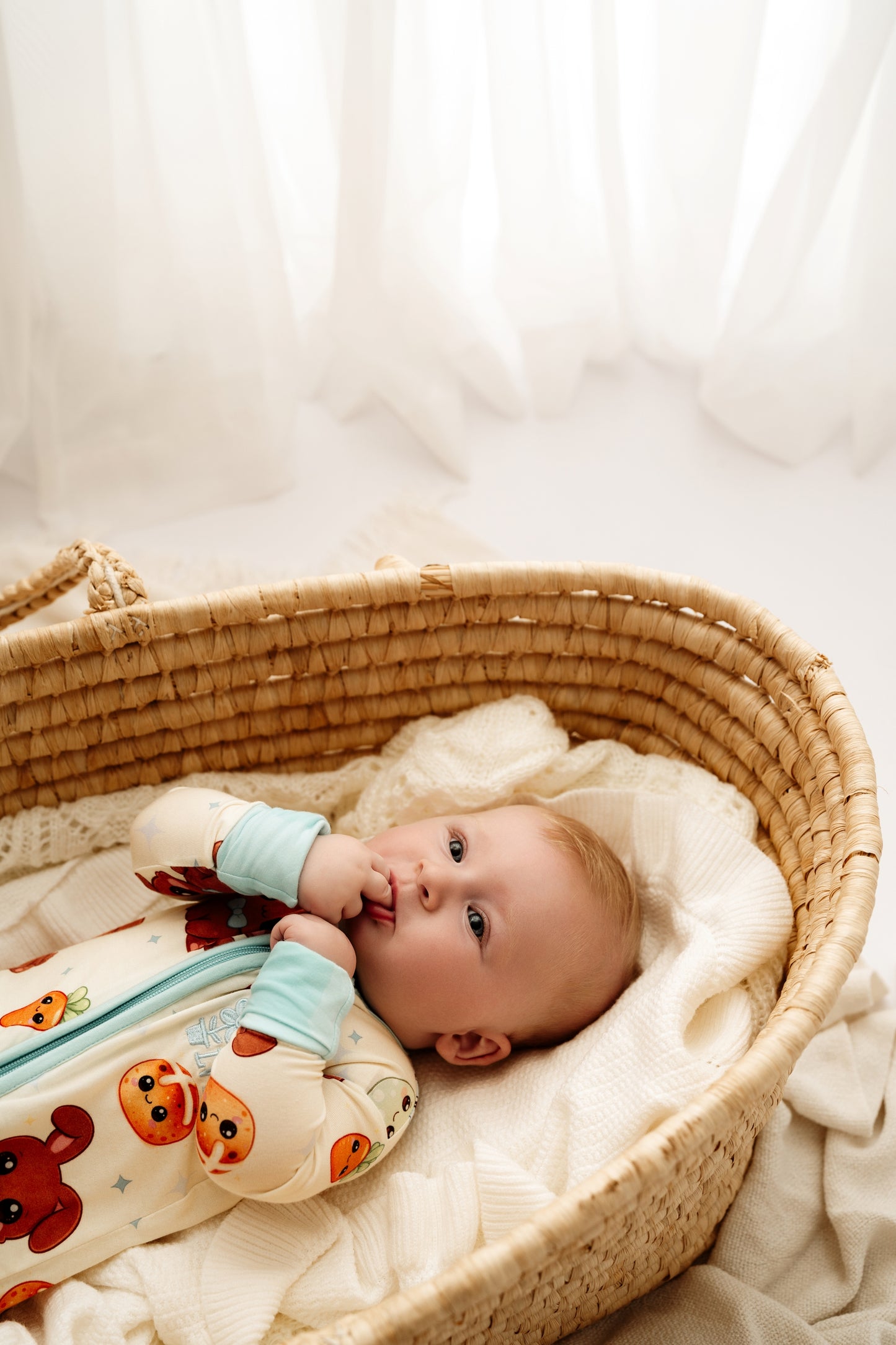 Baby lying in woven bassinet wearing Blue Bunny bamboo zip romper