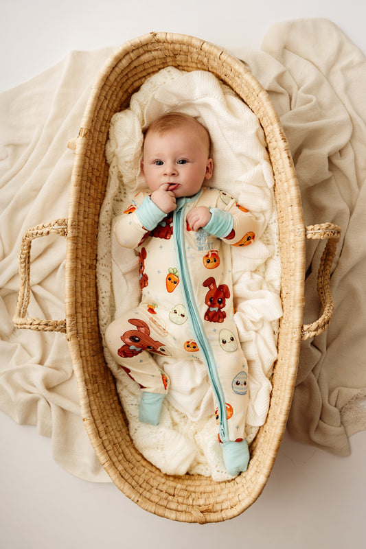 Baby wearing Blue Bunny bamboo zip romper lying in woven bassinet