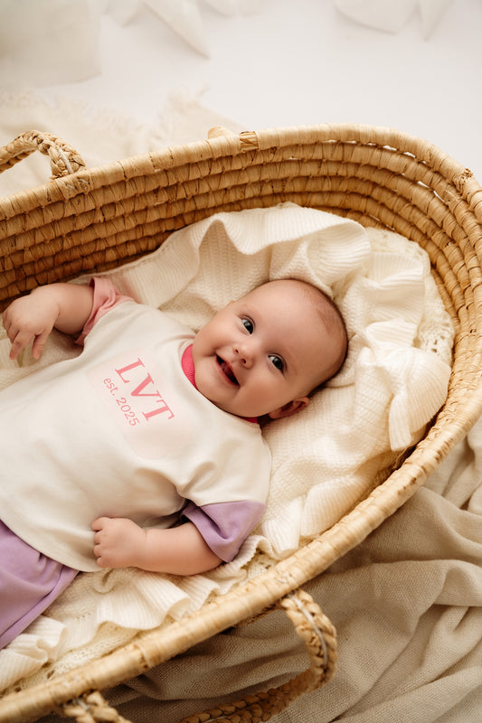 Baby wearing Pastel Dreams lounge set lying in woven bassinet