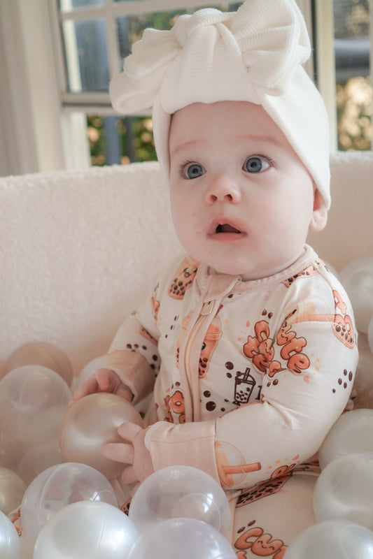 baby wearing little violet threads bubble tea baby bamboo zippy romper sitting with white balloons