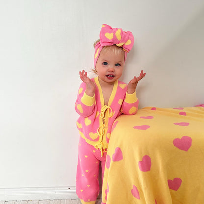 Baby girl wearing the Little Violet Threads Buttercup Princess pink and yellow cotton knit set with matching heart knit headband.