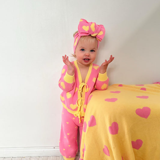 Baby girl wearing the Little Violet Threads Buttercup Princess pink and yellow cotton knit set with matching heart knit headband.