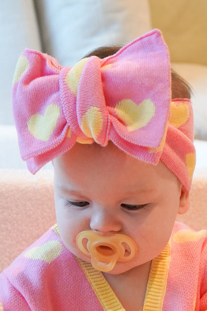 Baby girl wearing Buttercup Princess loveheart knit headband in pink and butter yellow cotton knit close up