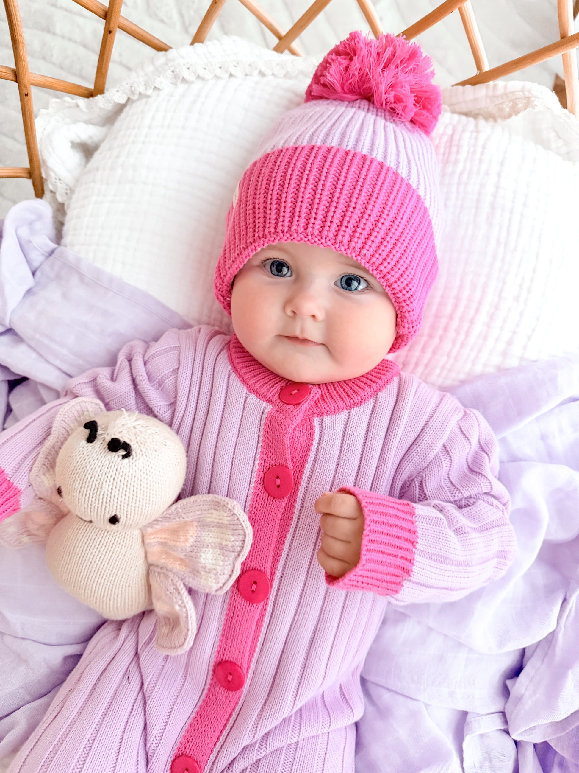 Baby girl in La Dolce Lollie Dream cotton knit romper and pink pom pom beanie
