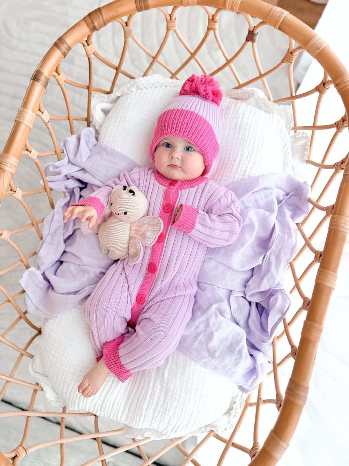 Baby wearing the La Dolce Lollie Dream Romper with matching pink and purple cotton knit beanie