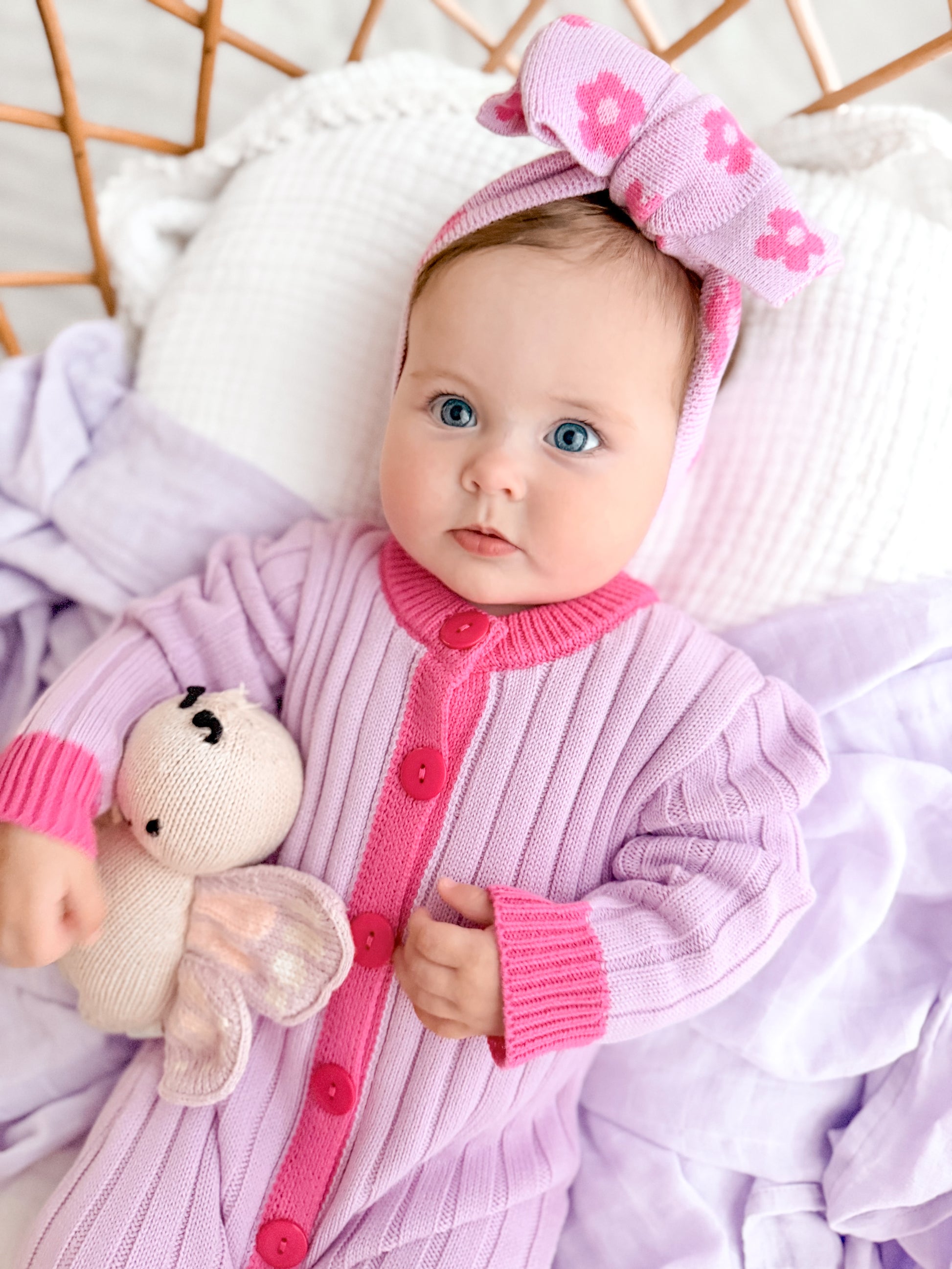 Baby girl wearing the La Dolce Lollie Dream Romper in purple and pink cotton knit with matching oversized bow