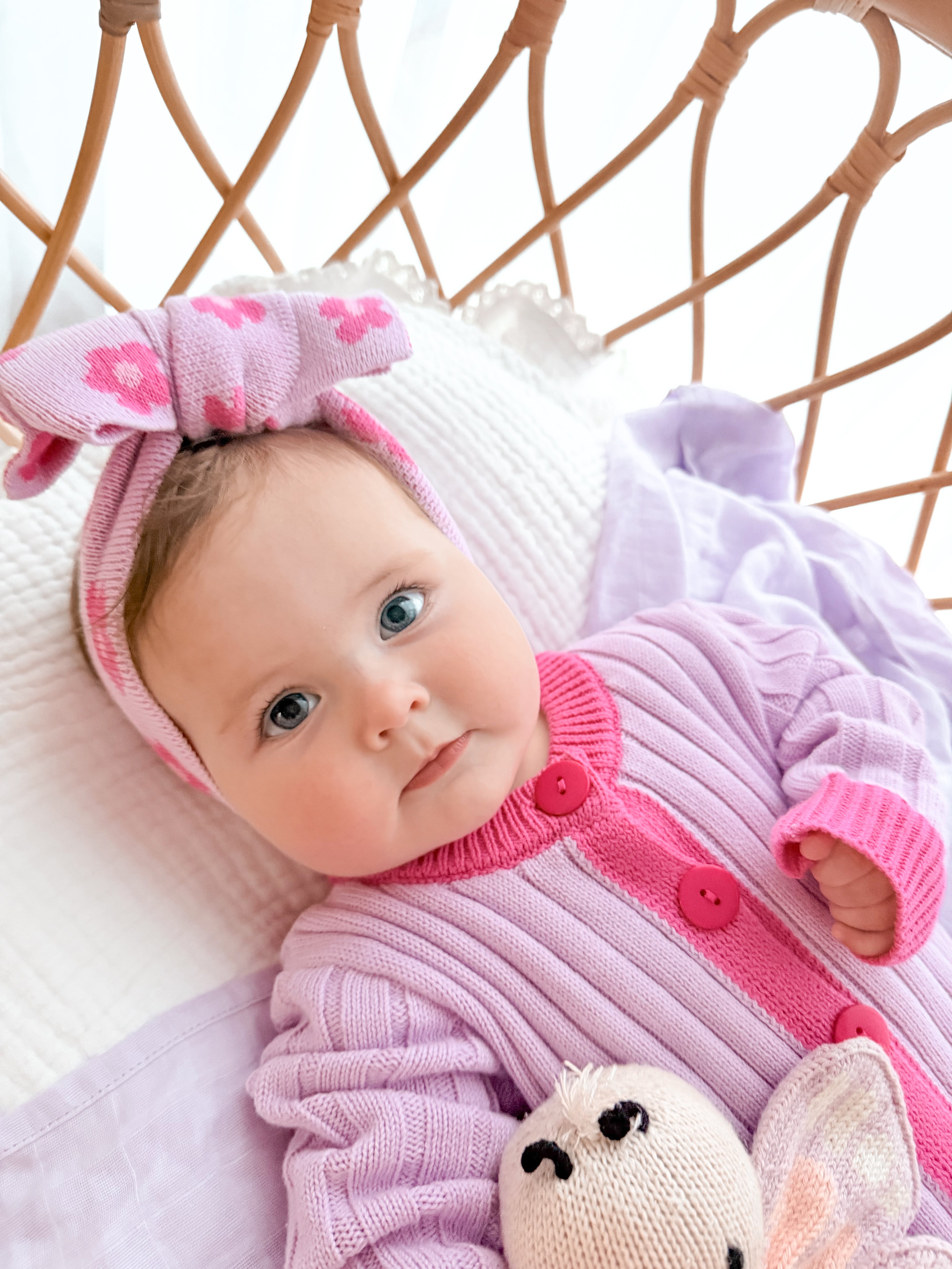 Baby wearing the La Dolce Lollie knitted head bow and matching pink and purple cotton knit romper