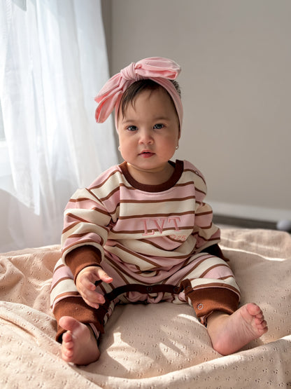 Baby wearing the Neapolitan French Terry romper by Little Violet Threads sitting on a soft blanket in pink, cream and chocolate stripes.
