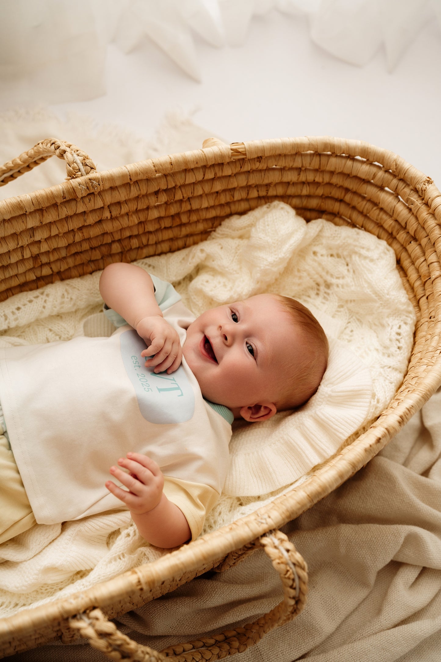 Smiling baby in bassinet wearing Pastel Maison pastel cotton lounge set
