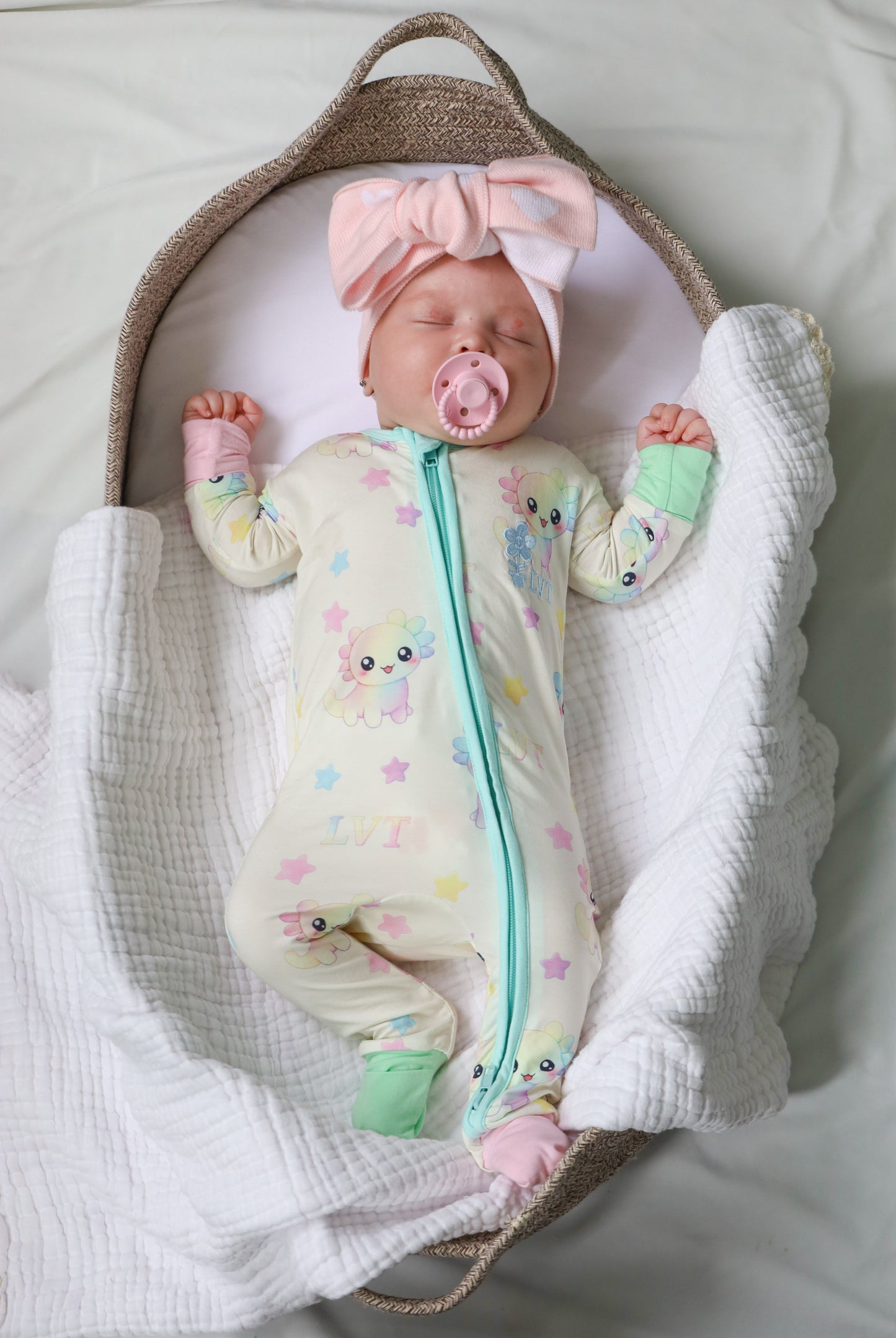 baby wearing little violet threads pastel bamboo baby zippy romper lying in bassinet