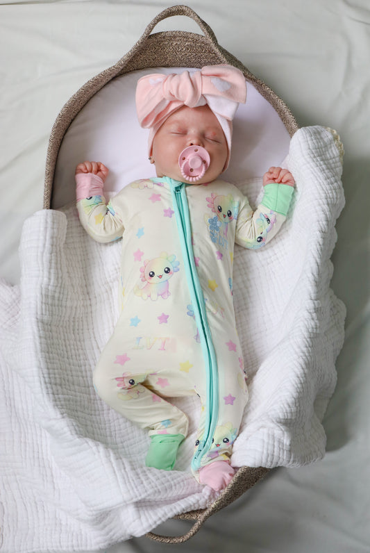baby wearing little violet threads pastel bamboo baby zippy romper lying in bassinet