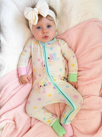 baby wearing little violet threads pastel bamboo baby zippy romper lying on pink blanket