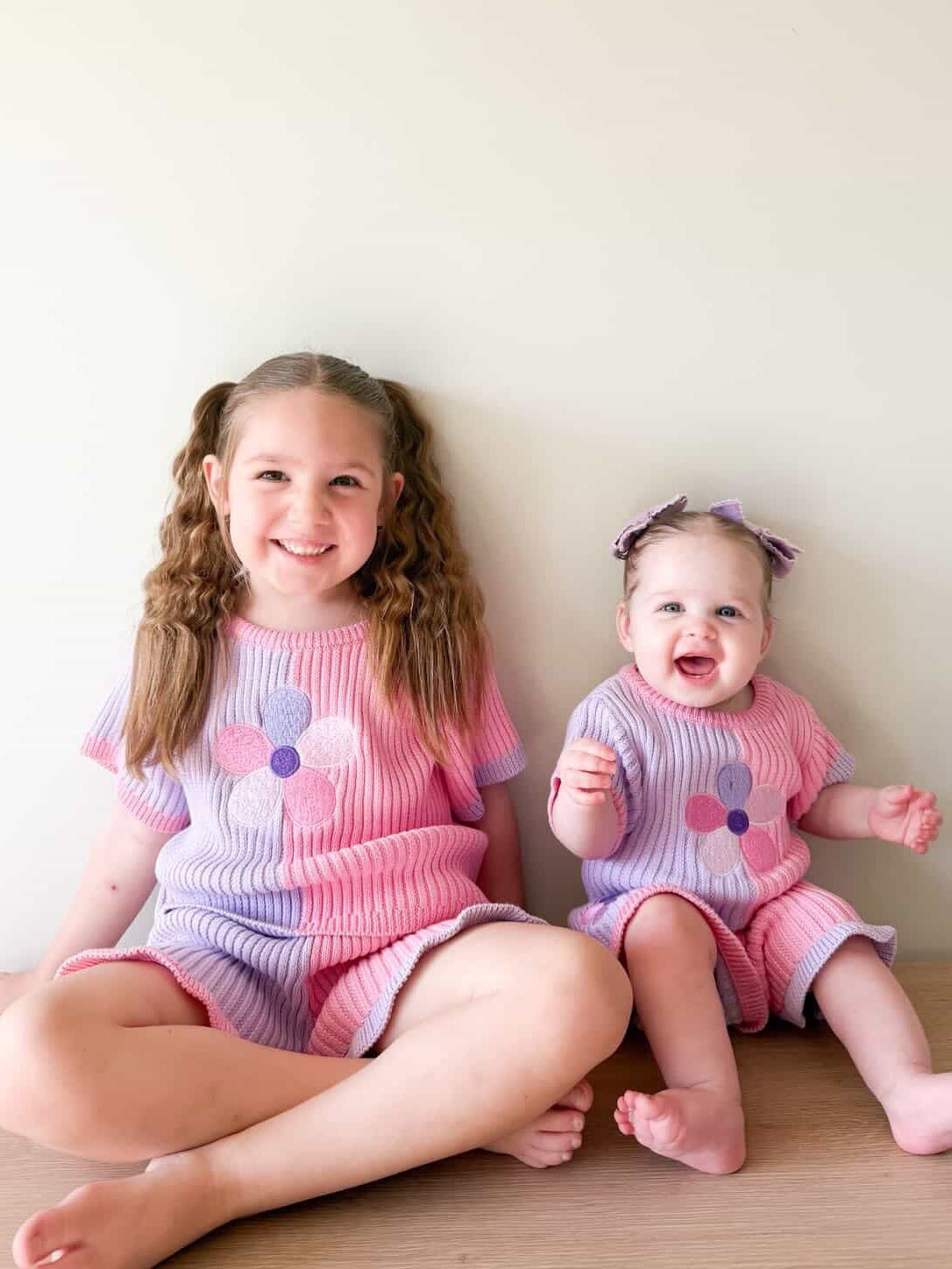Two girls wearing matching Little Violet Threads Petal Knit Sets from the La Dolce Lollie collection in pink and purple floral knit design