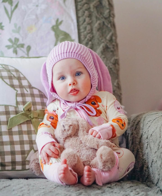 Baby wearing Pink Bunny bamboo baby zippy romper sitting with teddy bear