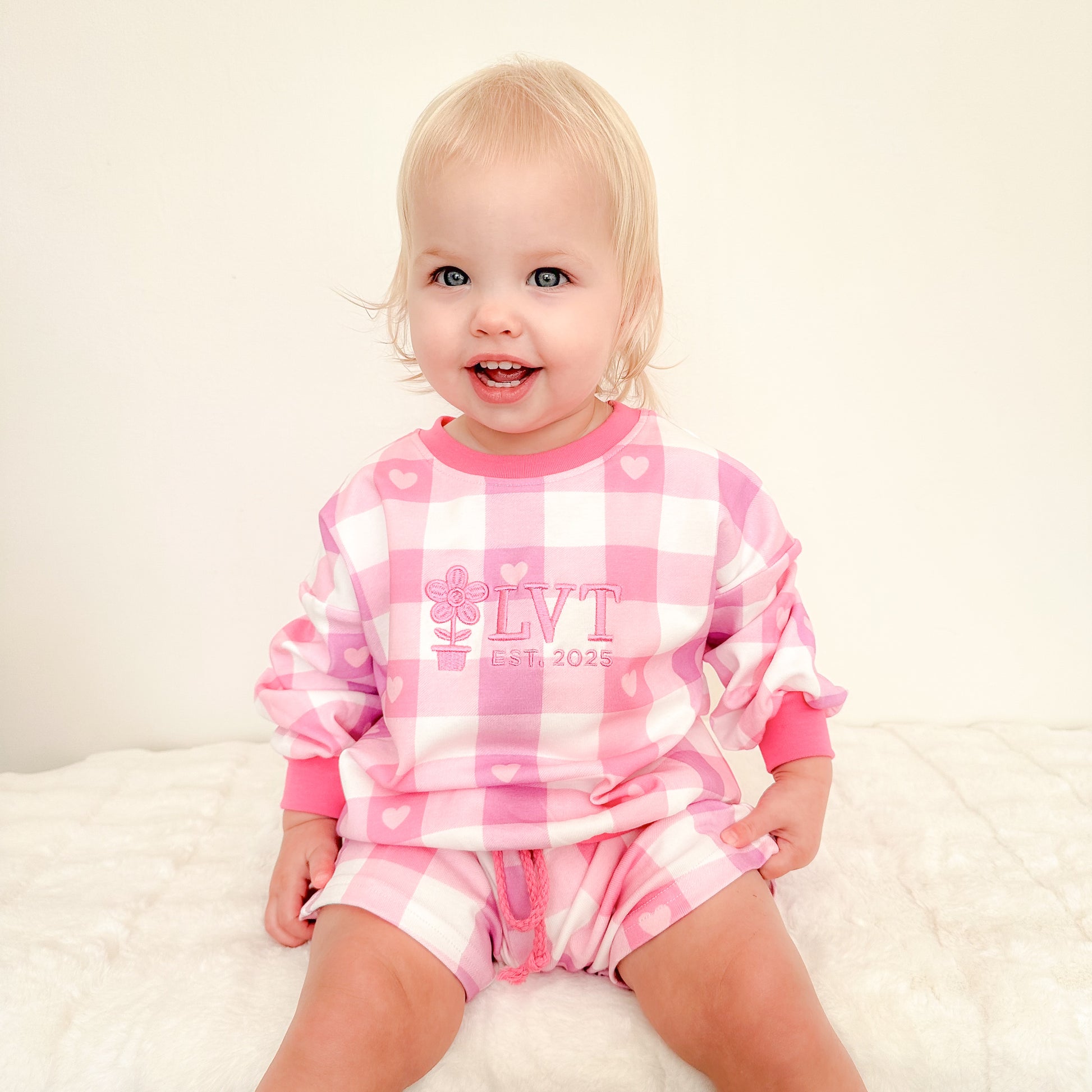 Toddler girl wearing Little Violet Threads Pink Sugar Lounge Set in pink gingham oversized jumper and matching shorts