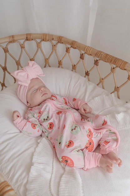 Baby wearing Strawberry Matcha bamboo zippy romper sleeping in wicker bassinet