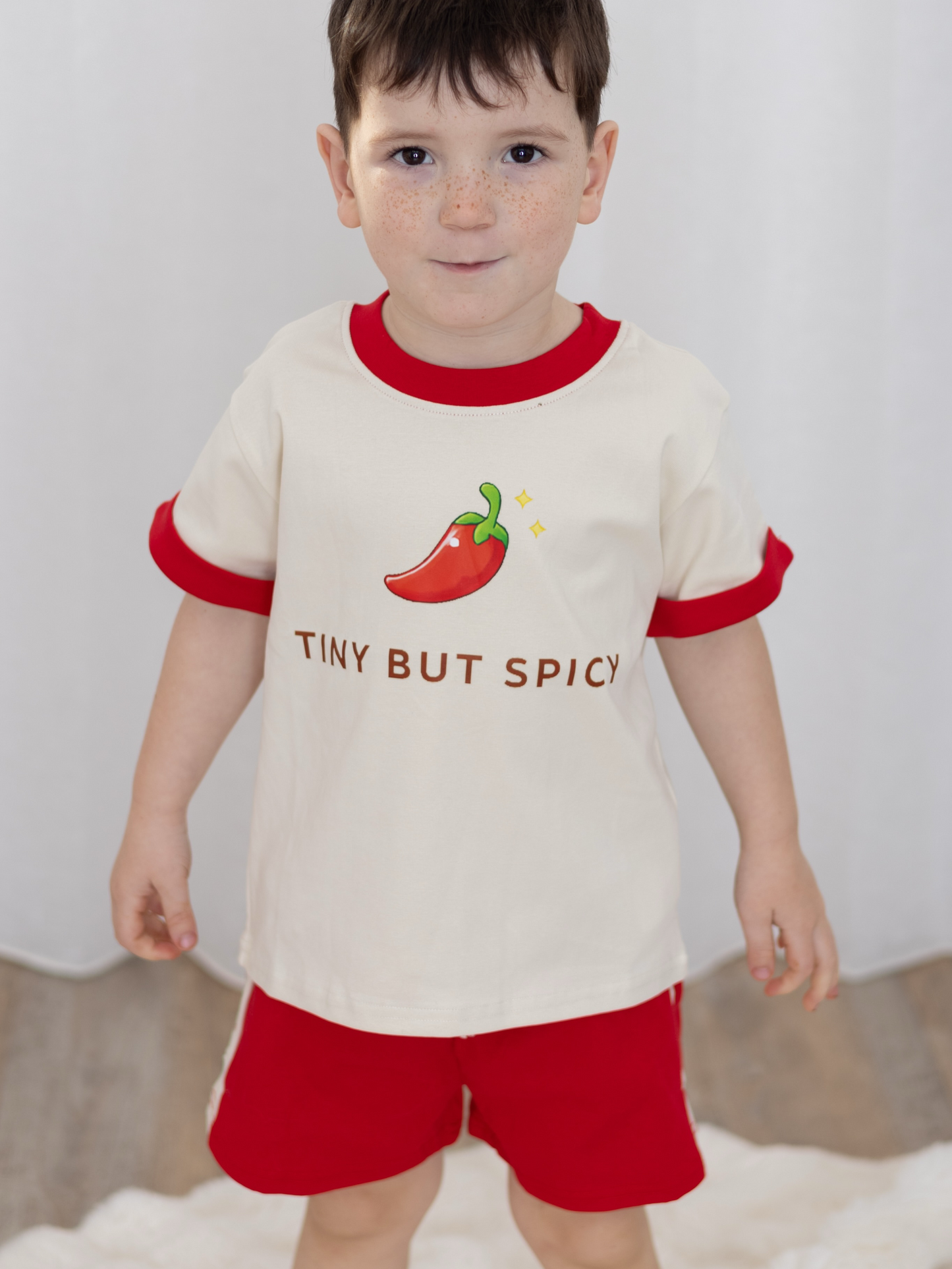 Child wearing our Tiny But Spicy matching kids set featuring oversized tee with chilli graphic and red relaxed shorts