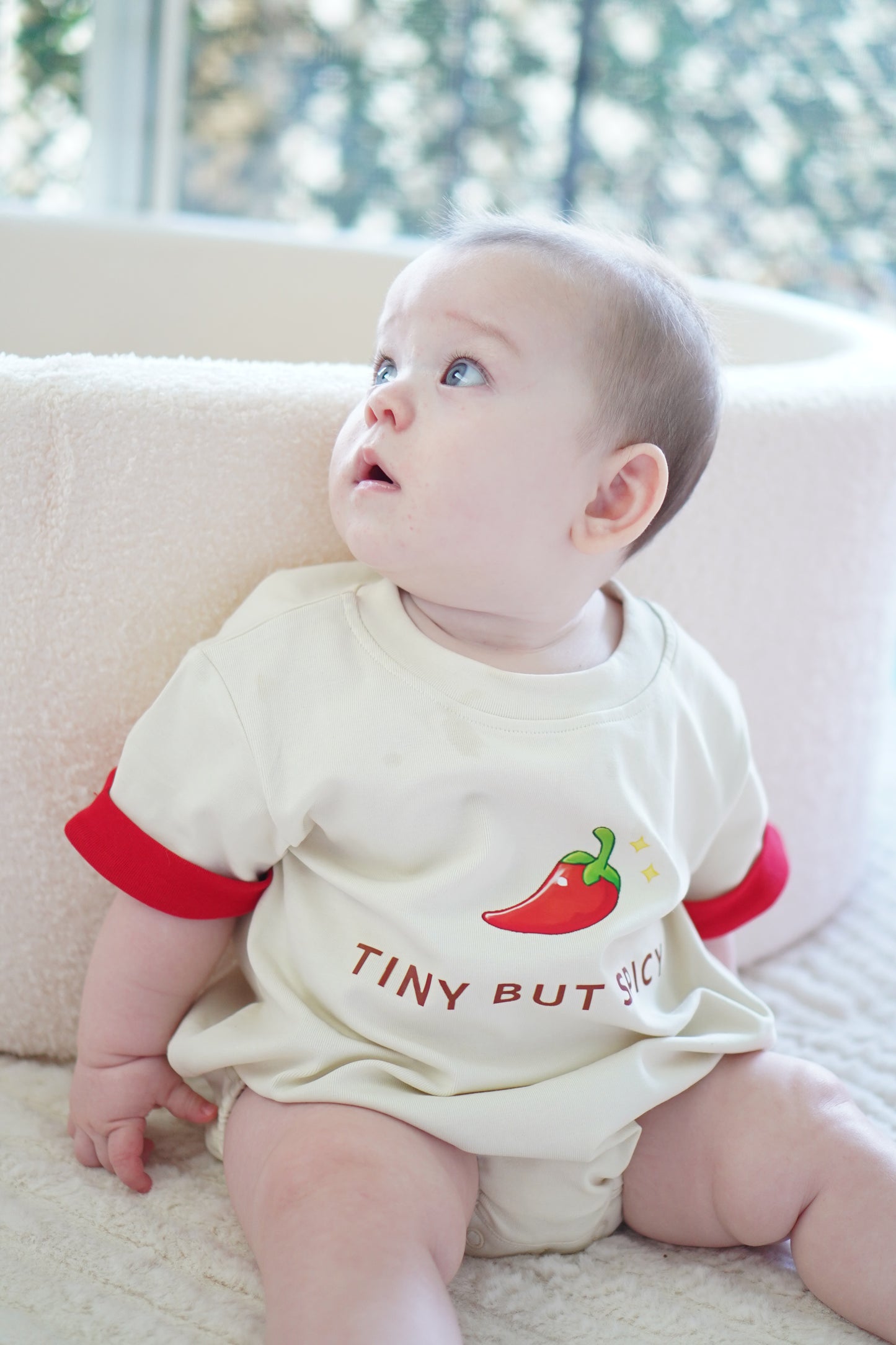 baby wearing little violet threads tiny but spicy oversized romper sitting on blanket