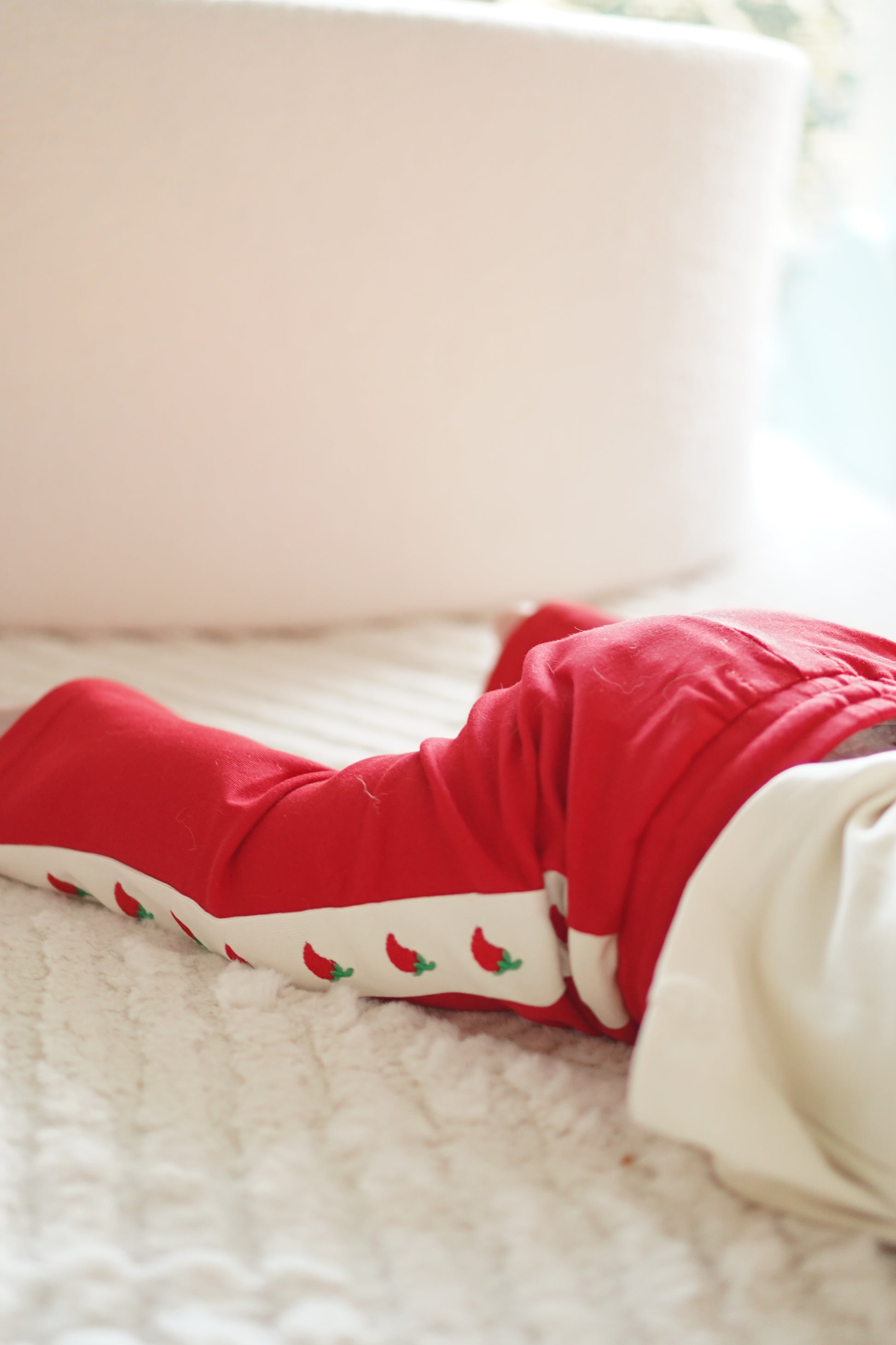close up of little violet threads tiny but spicy red flare pants with embroidered chilli detail