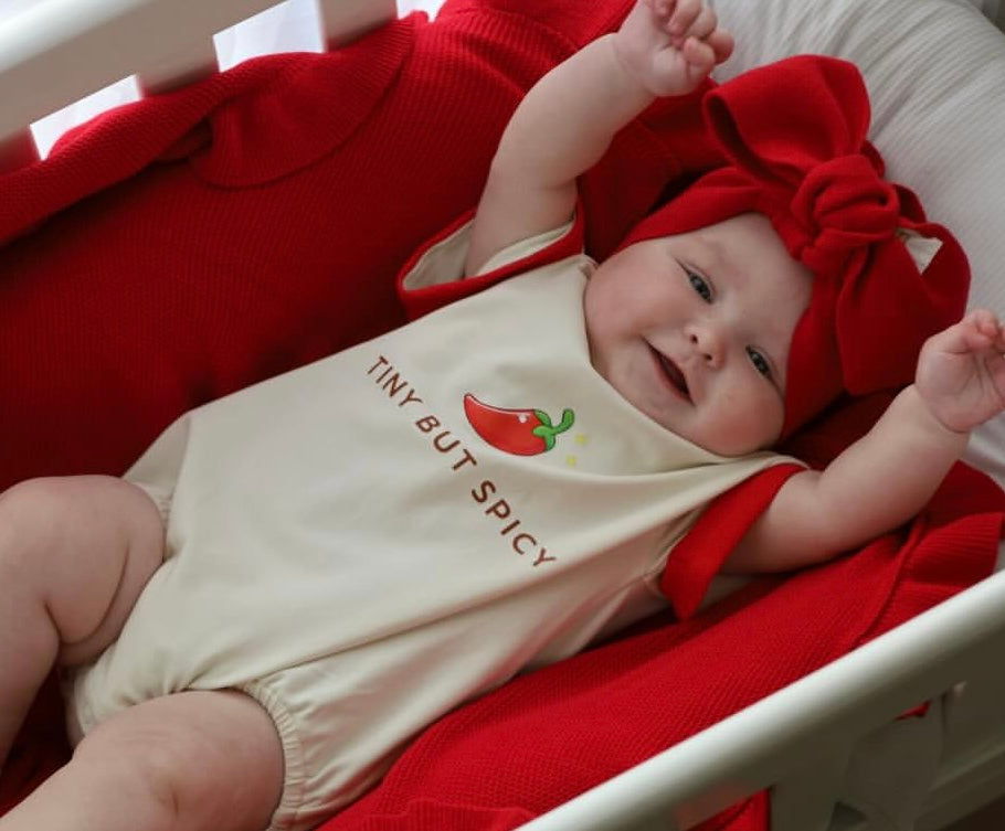 baby wearing little violet threads tiny but spicy romper with red bow headwrap