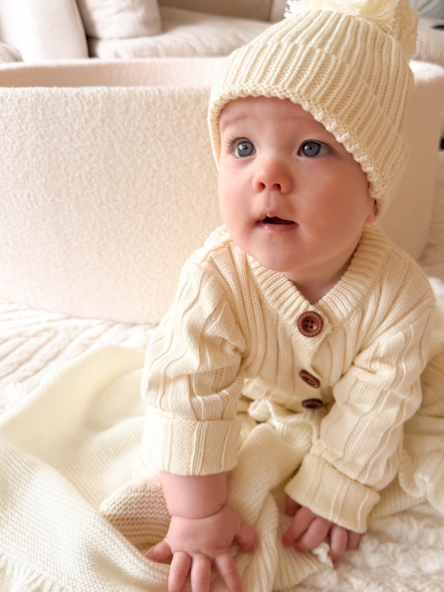 Baby wearing Vanilla Marshmallow cotton knit romper with matching cream beanie in neutral boutique baby outfit