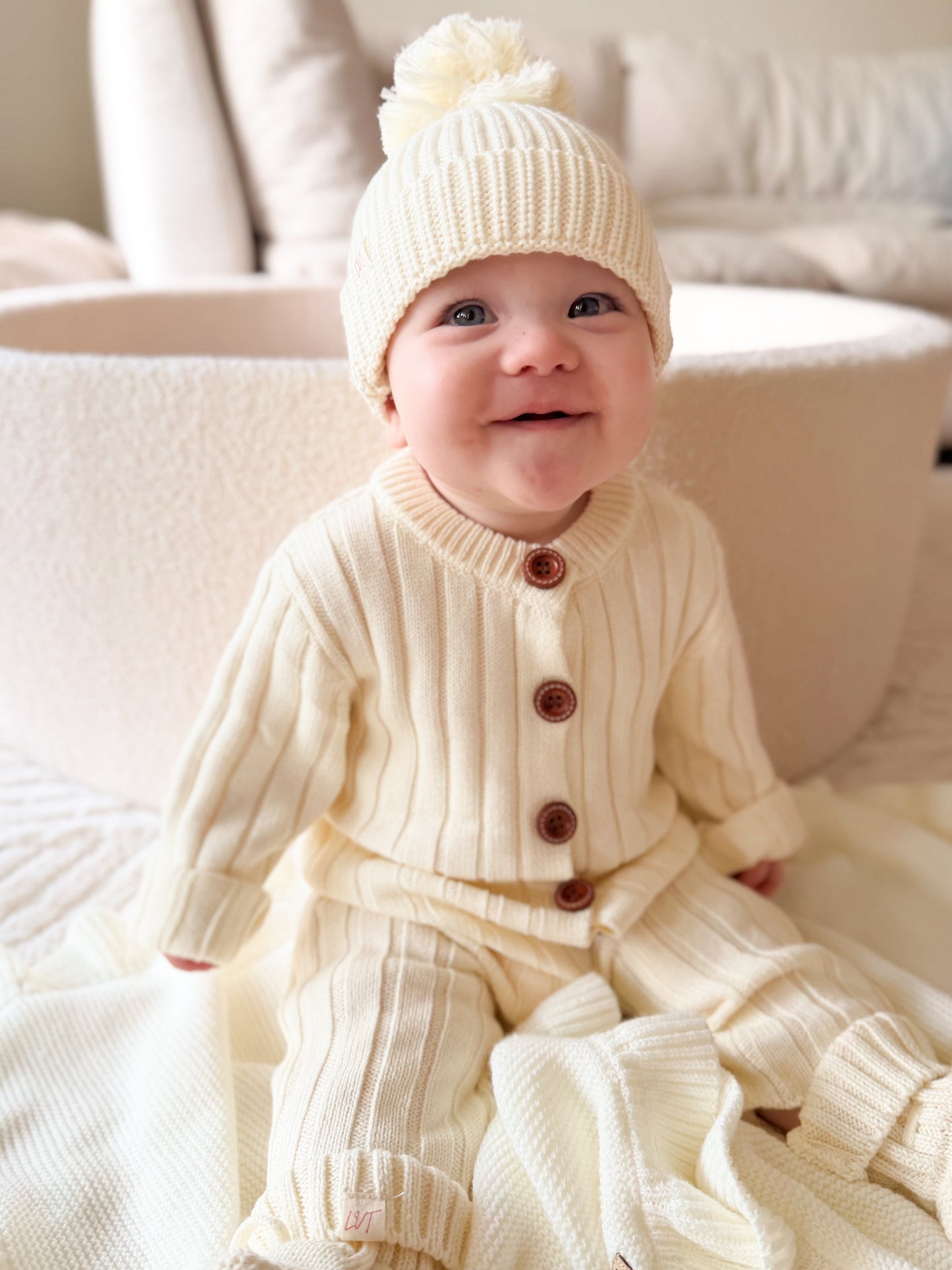 Vanilla Marshmallow cotton knit baby romper styled with matching cream beanie in boutique neutral baby outfit